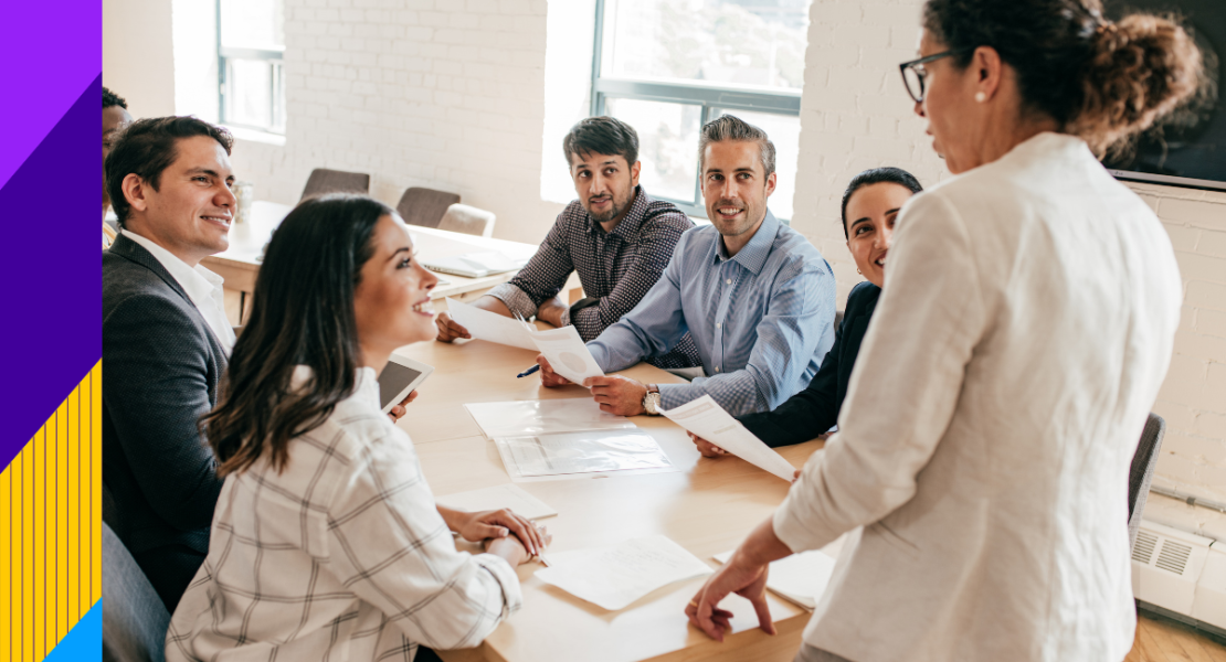 Men and women sitting at desk smiling at a women standing up