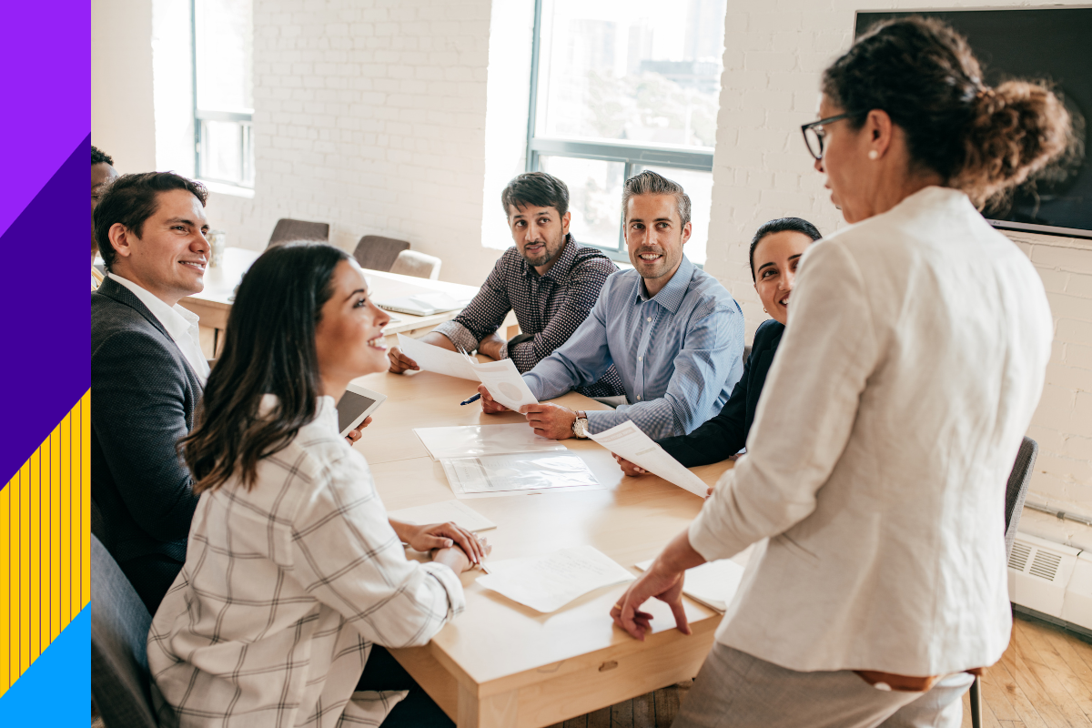 Men and women sitting at desk smiling at a women standing up
