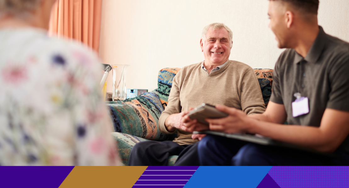 older man smiling and talking to a carer