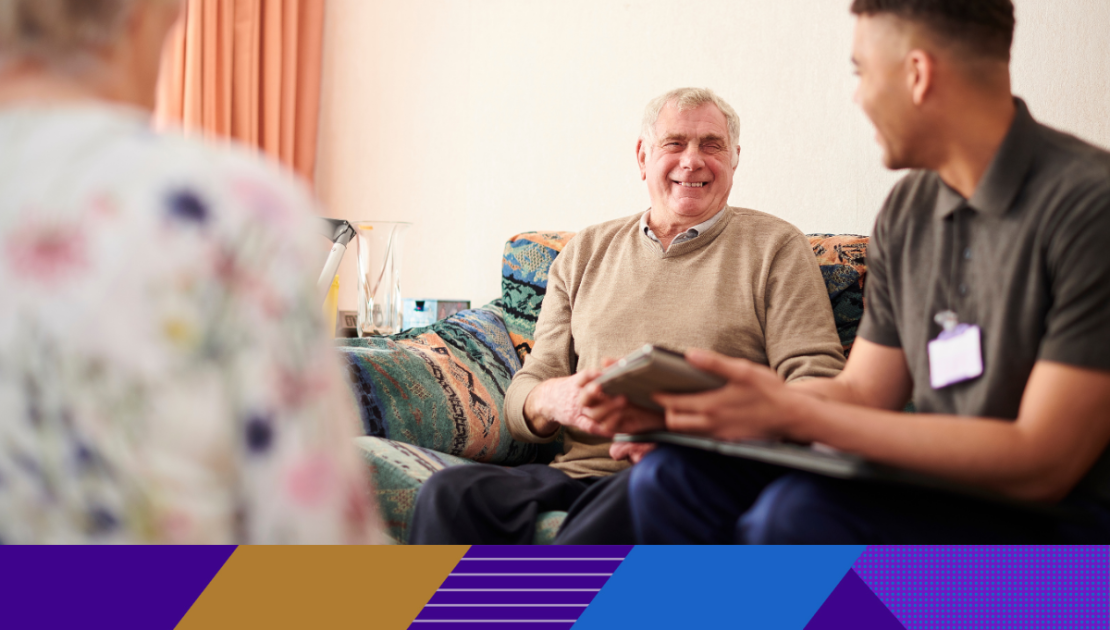 older man smiling and talking to a carer