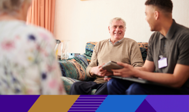 older man smiling and talking to a carer