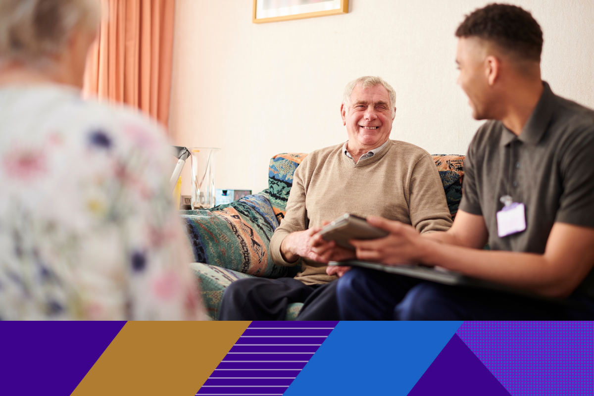 older man smiling and talking to a carer